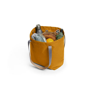 Bellroy Market Tote in mustard yellow with gray handles filled with groceries and daily essentials