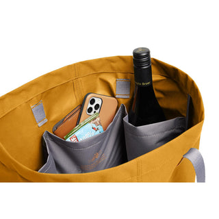 Bellroy Market Tote in mustard with internal grey pockets holding bottle phone and wallet