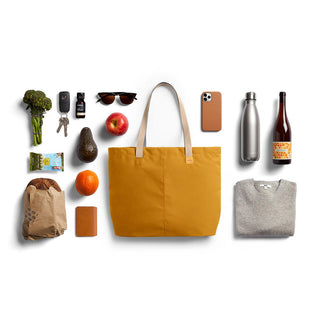 Bellroy Market Tote in mustard yellow fabric with leather handles and daily essentials arranged nearby