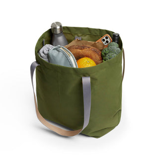 Bellroy Market Tote in green recycled nylon filled with groceries and personal items on white background