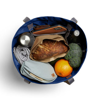 Bellroy Market Tote in blue with groceries and personal items inside, showing its spacious recycled nylon interior