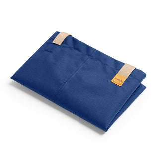 Folded navy blue Bellroy Market Tote made from recycled nylon with tan handles and orange logo tag