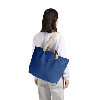 Bellroy Market Tote in blue recycled nylon carried over shoulder with beige straps on model back