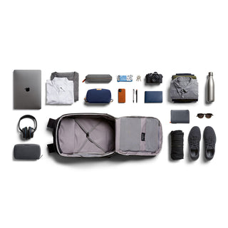Bellroy Transit Backpack Plus open with neatly arranged travel essentials on white background