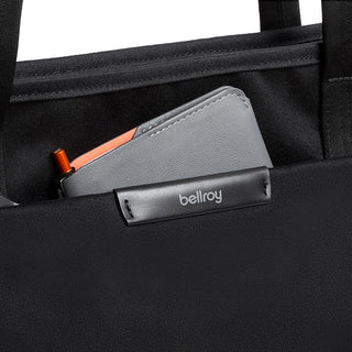 Close-up of black Bellroy Tokyo Tote Second Edition pocket holding a grey leather wallet with orange detail