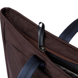 Bellroy Tokyo Tote Second Edition close-up showing dark brown woven fabric and navy handles with zipper pull detail