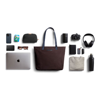 Bellroy Tokyo Tote Second Edition in dark woven fabric with leather handles and tech accessories arranged around it