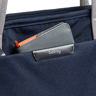 Bellroy Tokyo Tote Second Edition navy fabric with leather logo tag and a gray wallet in outer pocket