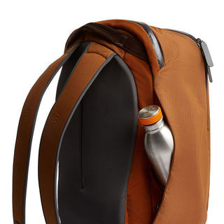 Bellroy Transit Workpack 20L in warm brown with padded straps and side pocket holding a metal bottle