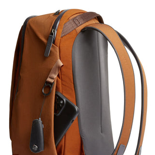 Bellroy Transit Workpack 20L in burnt orange with padded straps and side pocket holding a phone