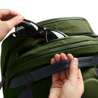 Bellroy Transit Workpack 20L in green with hand placing sunglasses in top zip pocket