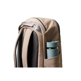 Bellroy Transit Workpack 26L in beige showing side pocket with blue water bottle and padded straps