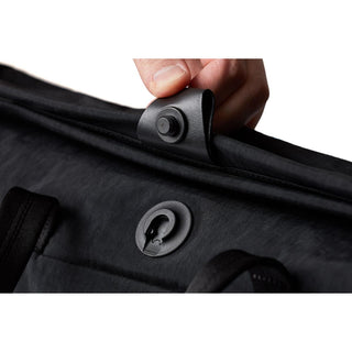 Close-up of black Bellroy Tokyo Messenger Bag 16" snap fastener detail held by hand