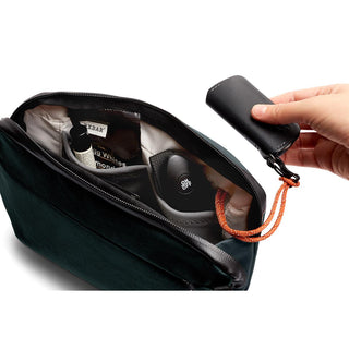 Bellroy Venture Travel Crossbody open showing interior pockets and organizer pouch with hand holding keychain accessory