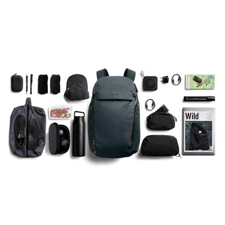 Bellroy Venture Travel Pack 26L in dark green with organized travel essentials laid out flat