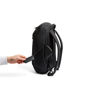 Bellroy Venture Ready Pack 20L black backpack showing a side pocket with a hand placing a wallet inside