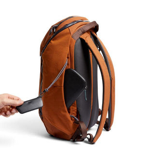 Bellroy Venture Ready Pack 20L in rust fabric shown from side with hand pulling black zipper pull tab