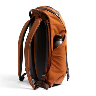 Bellroy Venture Ready Pack 20L in burnt orange with padded straps and side pocket holding water bottle
