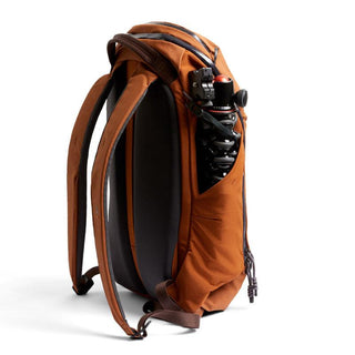 Bellroy Venture Ready Pack 20L in rust orange with side pocket holding a camera tripod