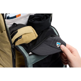 Bellroy Venture Ready Pack 20L laid open showing organized interior with folded clothes and a cap being placed inside