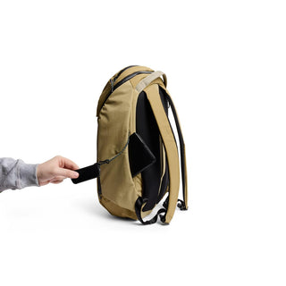 Bellroy Venture Ready Pack 20L tan backpack shown from the side with hand placing phone in hidden pocket