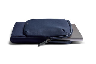 Bellroy Laptop Caddy 14" navy blue fabric sleeve with zipper and laptop partially inside