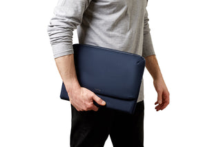 Bellroy Laptop Caddy 14" navy blue slim laptop sleeve held by person in gray shirt