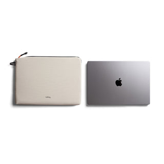 Bellroy Lite Laptop Sleeve 14" in beige recycled fabric next to a closed silver laptop on white background