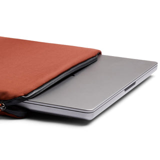 Bellroy Lite Laptop Sleeve 14" in rust fabric partially covering silver laptop on white background