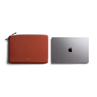 Bellroy Lite Laptop Sleeve 14" in rust color next to a silver laptop on white background