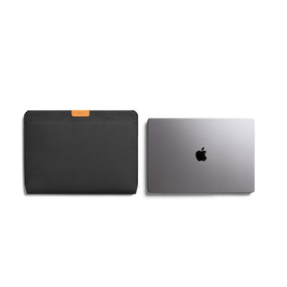 Bellroy Laptop Sleeve 16" in black recycled fabric with tan leather tab alongside a silver laptop