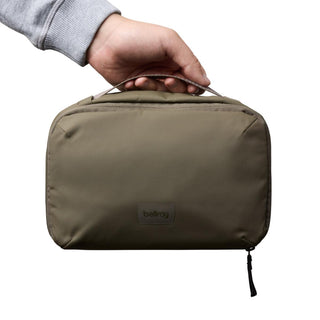 Hand holding olive green Bellroy Hanging Toiletry Kit made from recycled nylon with top handle