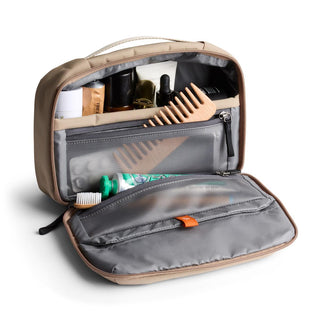 Bellroy Hanging Toiletry Kit in tan with organized compartments and a wooden comb inside