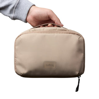 Bellroy Hanging Toiletry Kit in beige with soft fabric and top handle held by hand