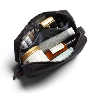 Bellroy Toiletry Kit open with organized travel bottles and personal care items inside black fabric pouch