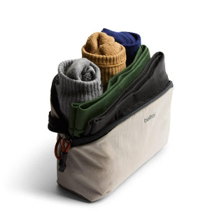 Bellroy Lite Packing Pouch 2L in beige with rolled clothes, showing compact and eco-friendly travel storage