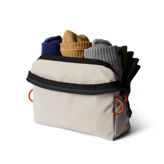 Bellroy Lite Packing Pouch 2L in neutral fabric with black trim holding four pairs of colorful socks