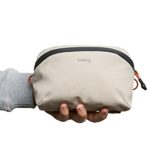 Bellroy Lite Packing Pouch 2L in beige recycled nylon held in hand showing compact size and zipper detail
