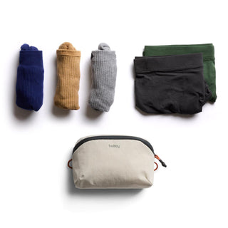 Bellroy Lite Packing Pouch 2L in beige with black zipper shown alongside folded socks and underwear