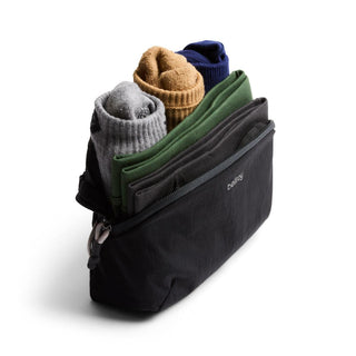 Bellroy Lite Packing Pouch 2L in black holding neatly rolled clothes with visible zipper and fabric texture