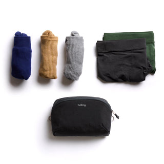Bellroy Lite Packing Pouch 2L in black recycled nylon with folded clothes and socks nearby on white background