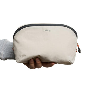 Hand holding Bellroy Lite Packing Pouch 3L in beige with black zipper and textured recycled fabric