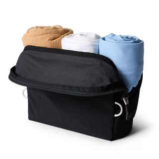 Bellroy Lite Packing Pouch 3L black fabric pouch with rolled beige, white, and blue clothes inside