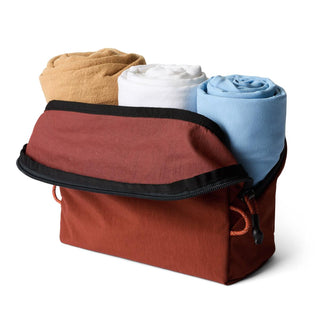 Bellroy Lite Packing Pouch 3L in rust red, partially open showing rolled clothes inside