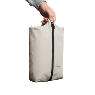 Bellroy Lite Packing Caddy 8L in light beige recycled fabric with central zipper held by hand