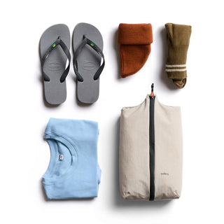 Bellroy Lite Packing Caddy 8L filled with organized clothes and flip flops on white background