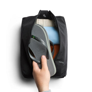 Bellroy Lite Packing Caddy 8L in black with zipper open showing packed shoes and clothing inside