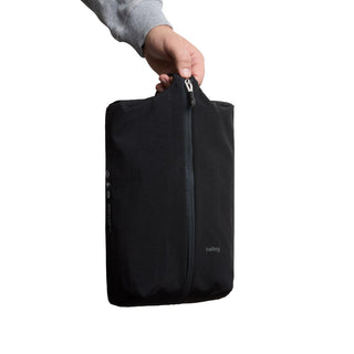 Bellroy Lite Packing Caddy 8L in black recycled nylon held by hand with vertical zipper closure
