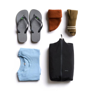 Bellroy Lite Packing Caddy 8L in black with travel essentials including shirt, socks, and sandals arranged neatly
