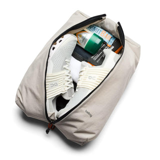 Bellroy Lite Packing Caddy 10L in light beige, open with gym shoes and small travel essentials inside